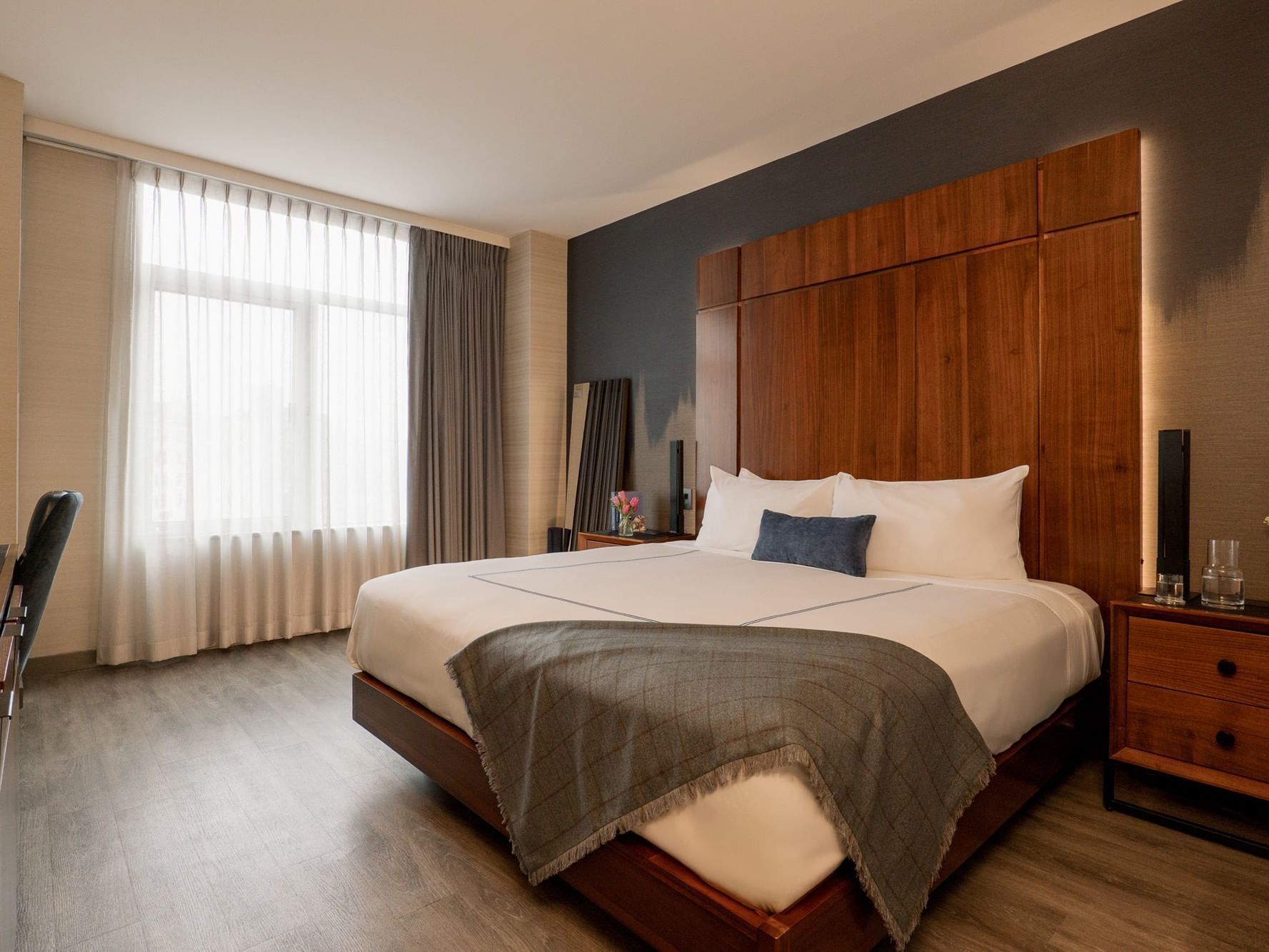 Accessible Superior Room with wooden bed, gray blanket, and white curtains at Gansevoort Meatpacking NYC, New York.