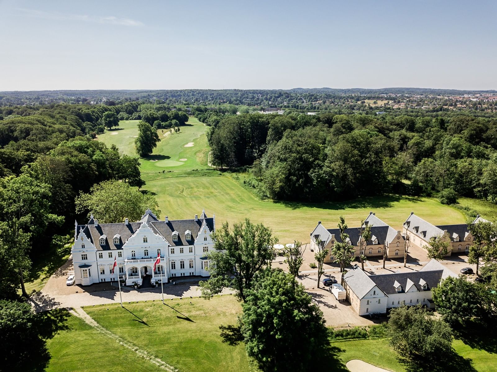 High-angle aerial view of Warwick Denmark hotel surrounded by a lush green golf course