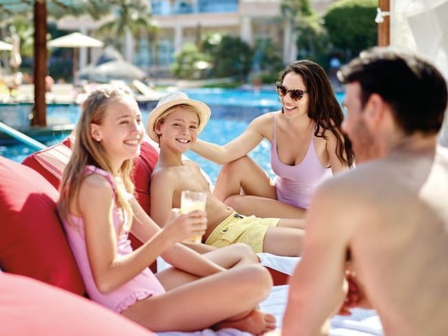 Family having fun by the outdoor swimming pool at Gamma Resort