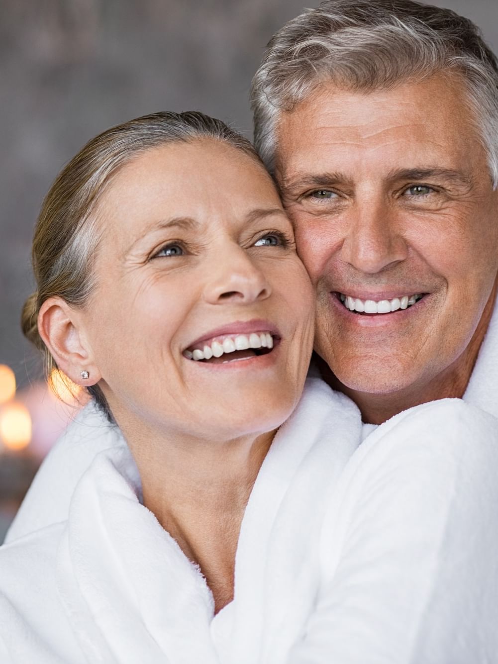 Un couple de seniors en peignoir souriant pour une offre destinée aux voyageurs seniors.