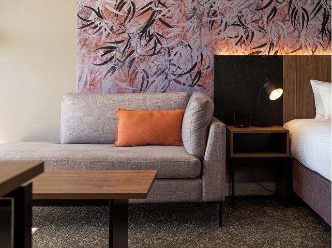 Sofa with a table next to the bed in a room at Novotel Barossa