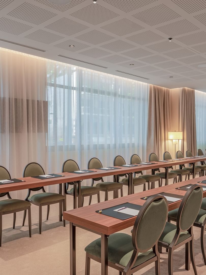 U-shaped table with green cushioned chairs and large windows in the Warwick meeting room at Warwick Reine Astrid - Lyon