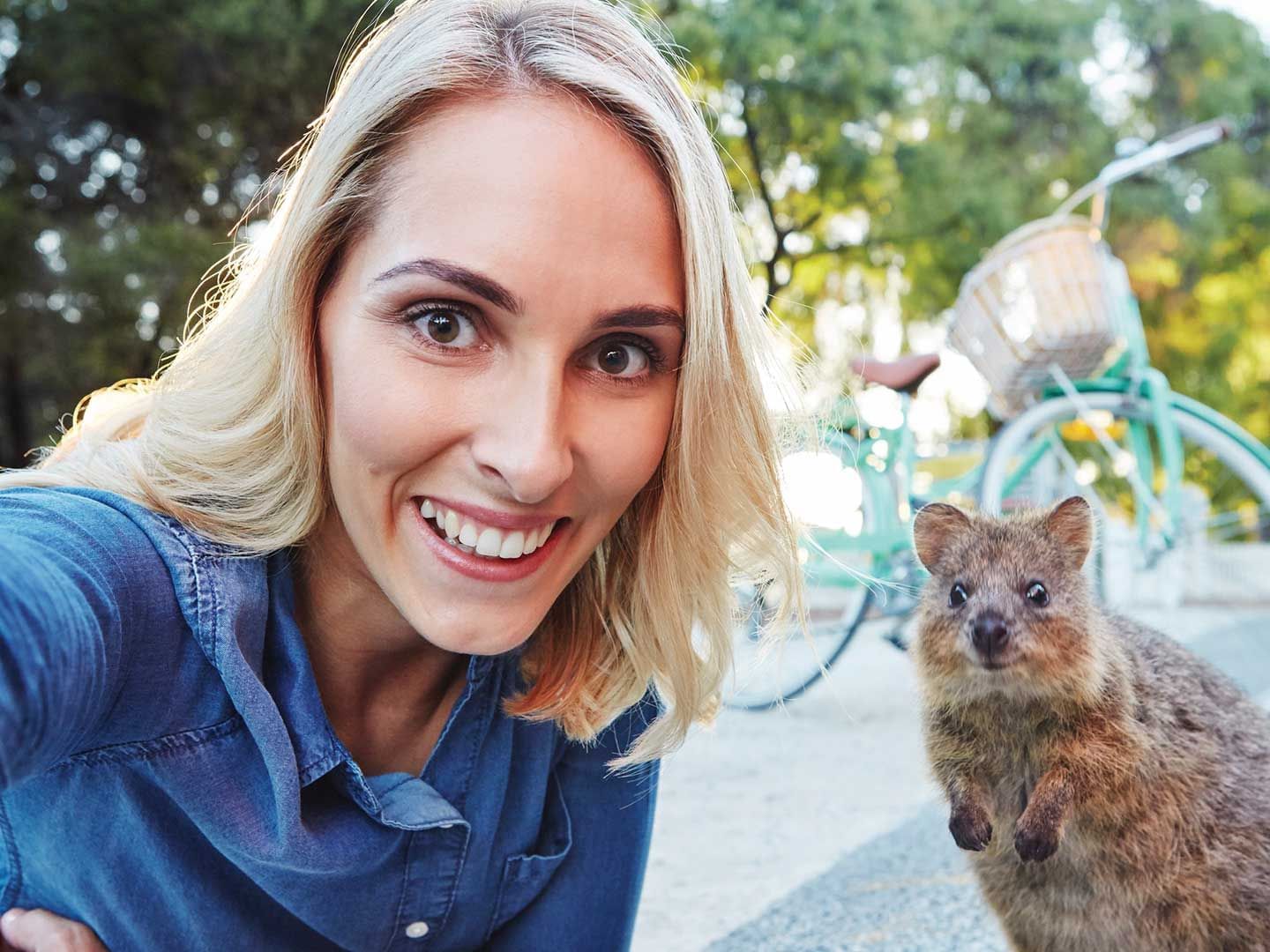 A woman taking a picture with a quokka at Rottnest Island near Be Fremantle