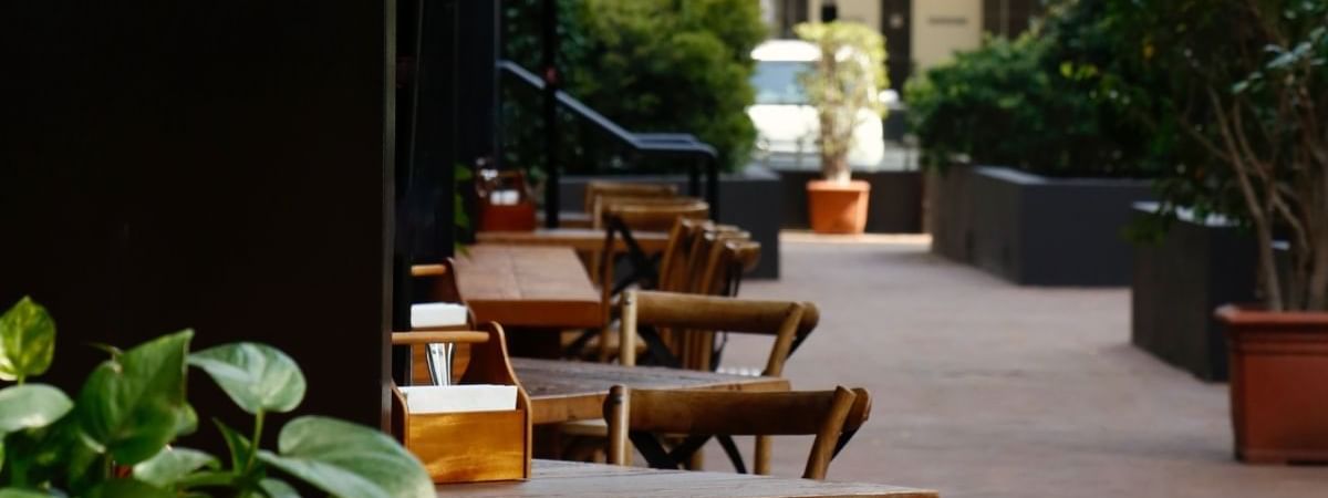 Outdoor dining terrace with wooden tables and chairs at Novotel Sydney International Airport