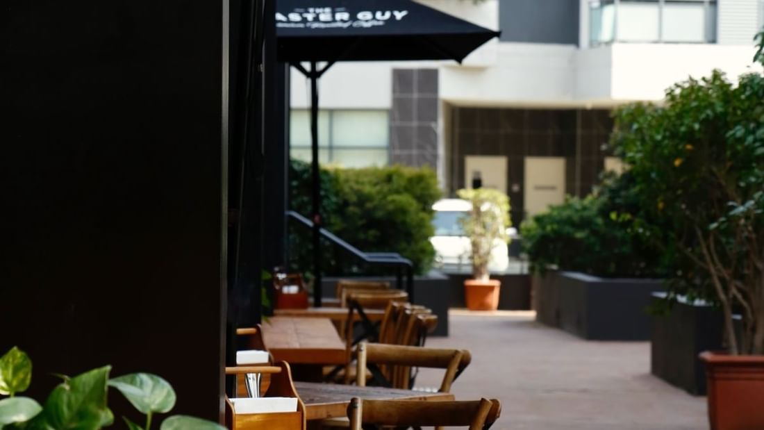 Outdoor dining terrace with wooden tables and chairs at Novotel Sydney International Airport