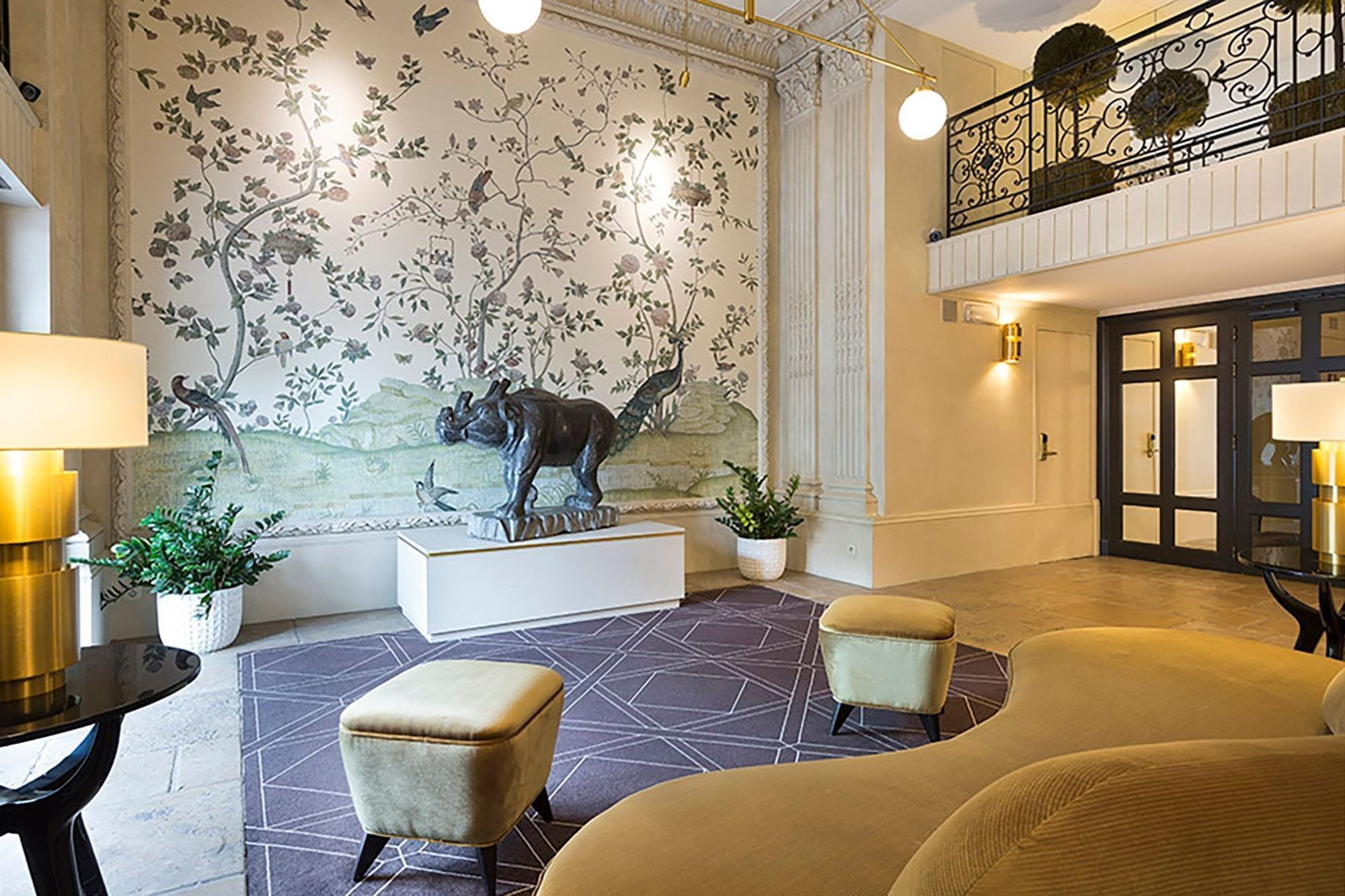Floral mural with rhino sculpture, and velvet seating in the lobby of Hotel Barsey by Warwick