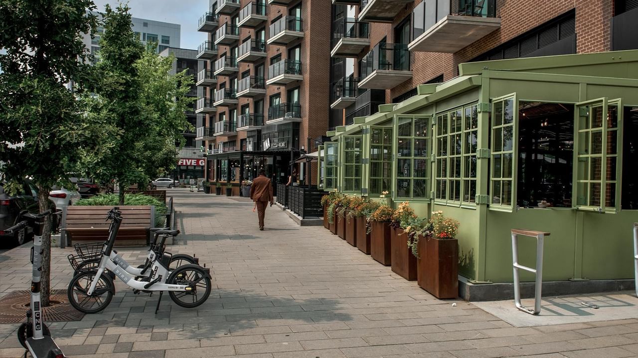 Pedestrian-friendly street with modern retail shops, outdoor seating, and residential buildings in University District