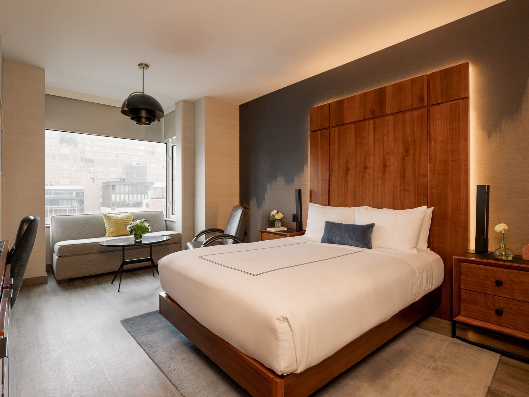 Interior of a Grand Deluxe Room with a bed and couch at Gansevoort Meatpacking NYC in New York.
