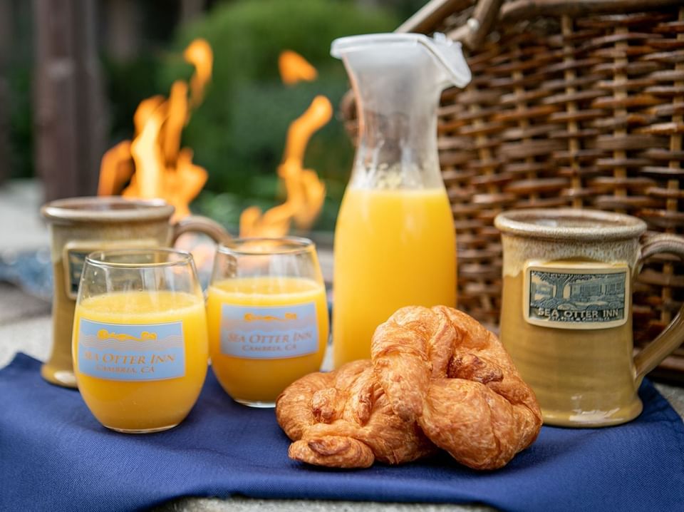 Orange juice and croissants on a blue cloth by a woven basket at Sea Otter Inn