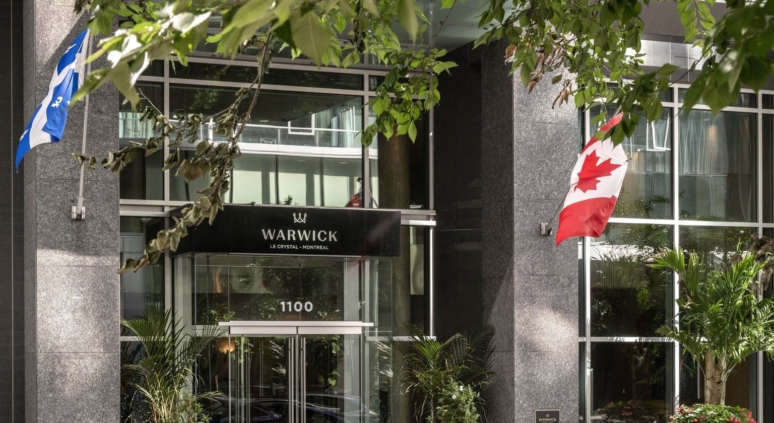 Voiture bleue devant l'hôtel Warwick Le Crystal de Montréal avec drapeaux canadien et québécois à Warwick Le Crystal Montreal