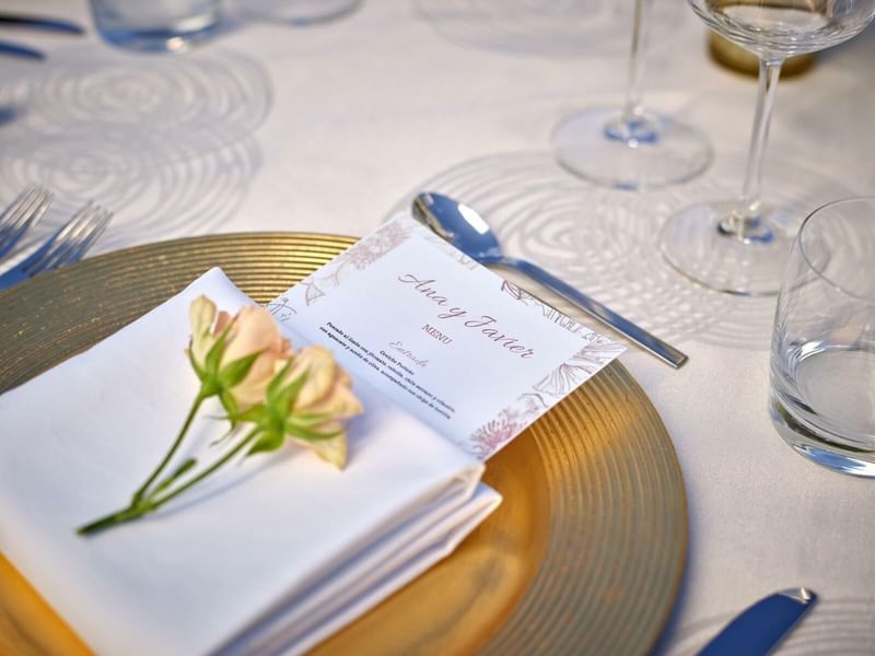 A wedding invitation & roses on a table at Live Aqua Resorts