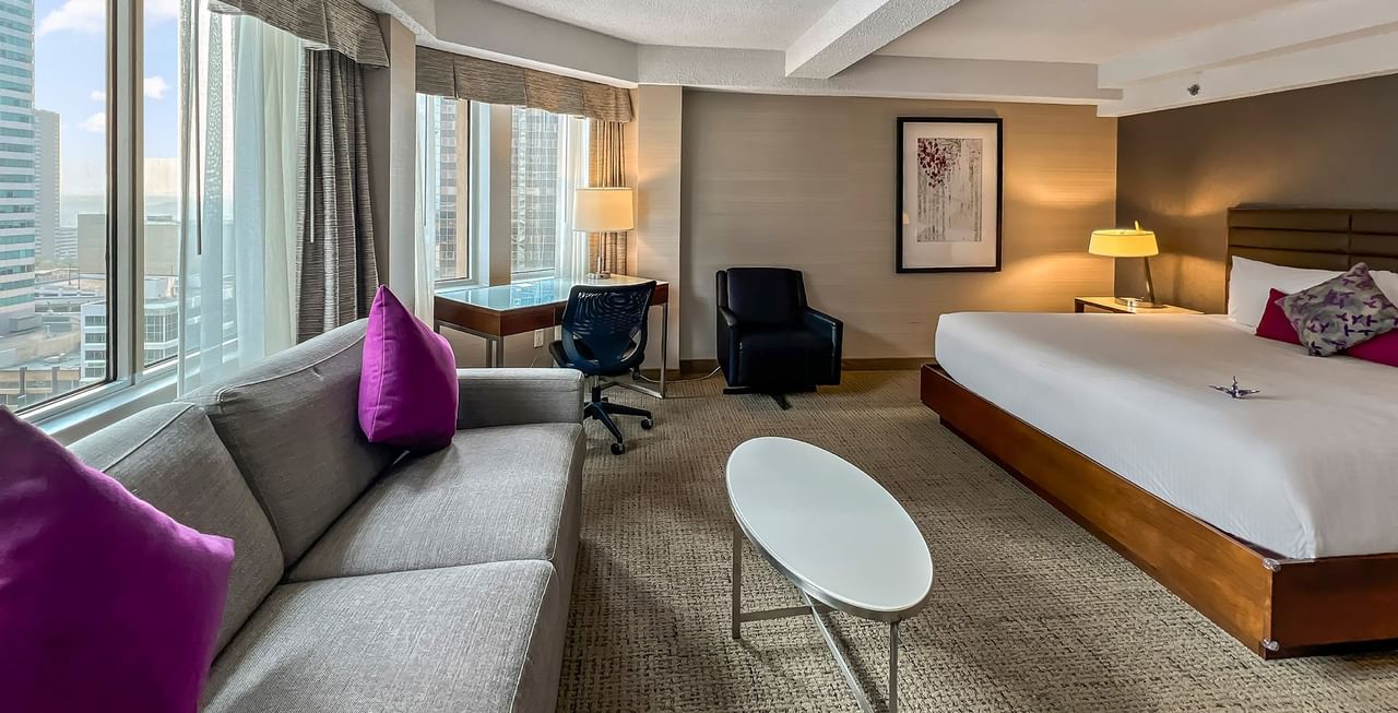 Hotel room with king bed, sofa bed, working desk, table, and a view