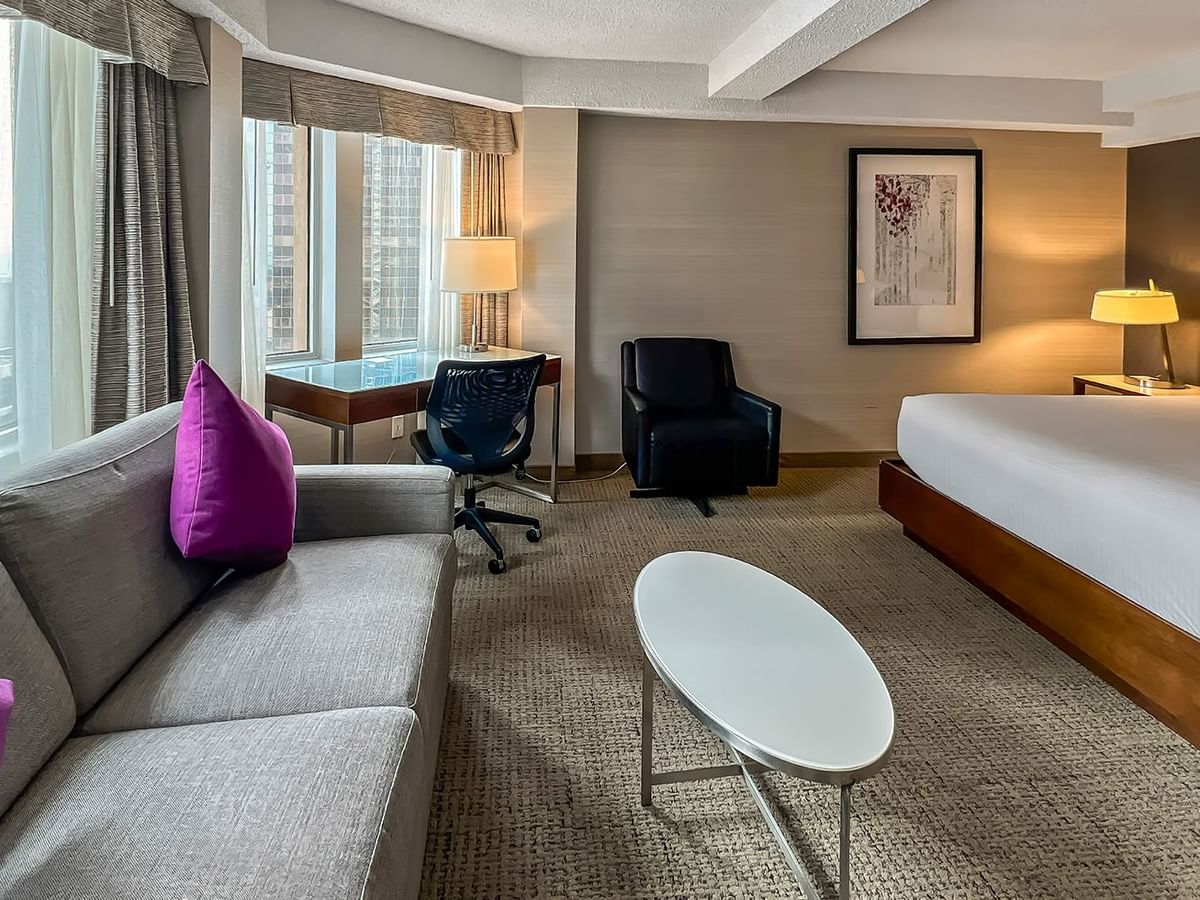 Hotel bedroom with bed, sofa bed, TV, and table