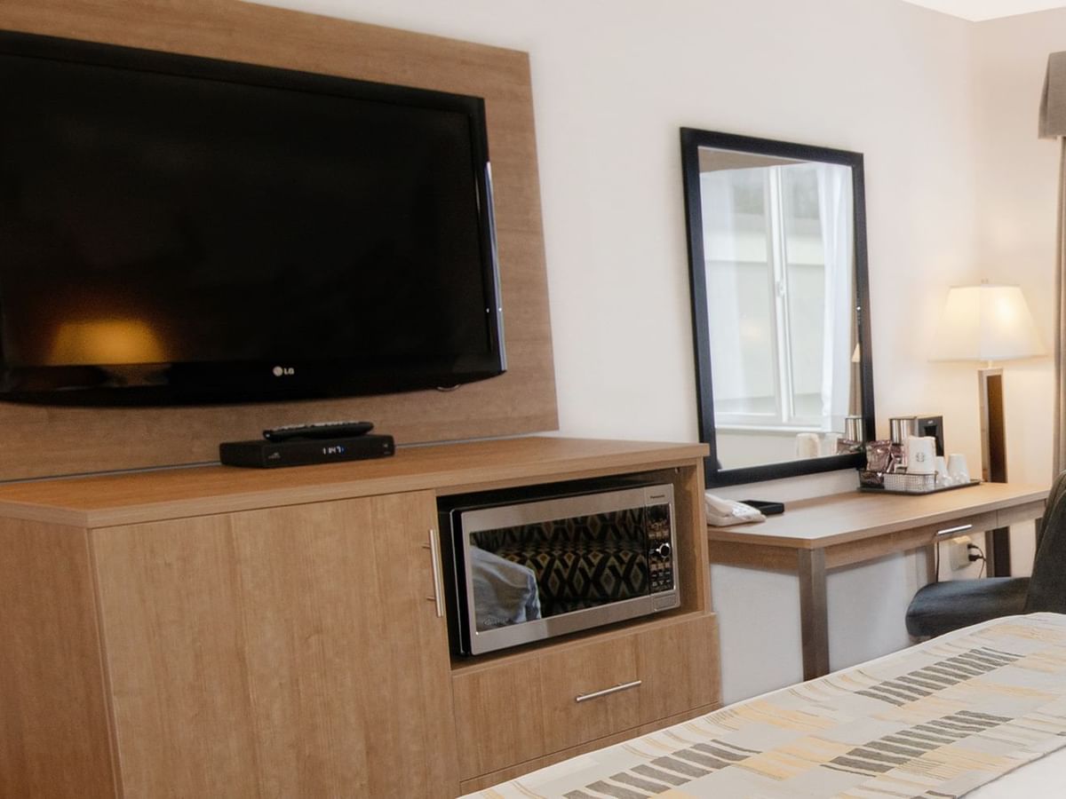 Hotel room with TV, microwave, bed, mirror, chair, and desk