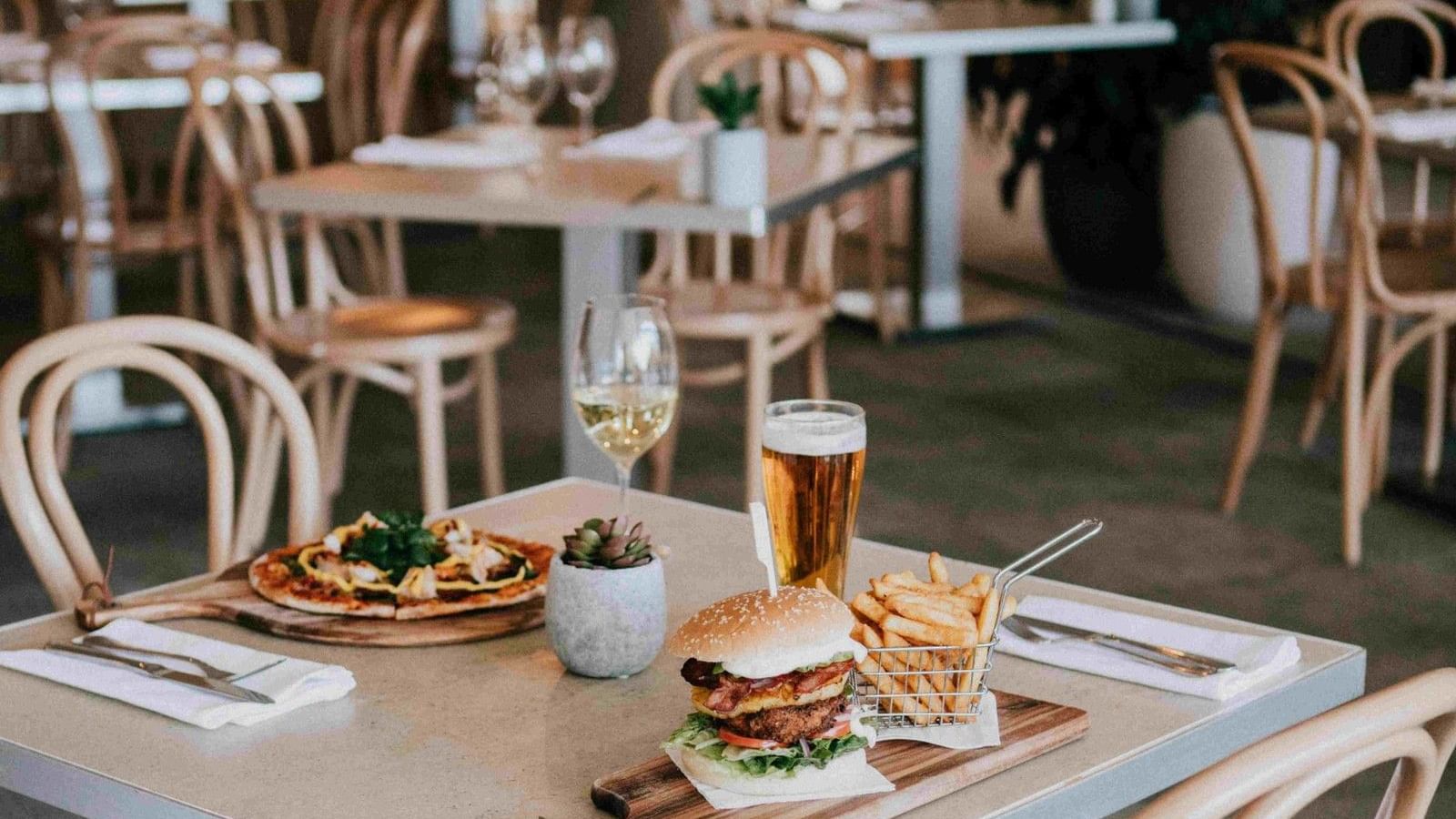 Empty restaurant dining area with table set for two and food at Mercure Charlestown.