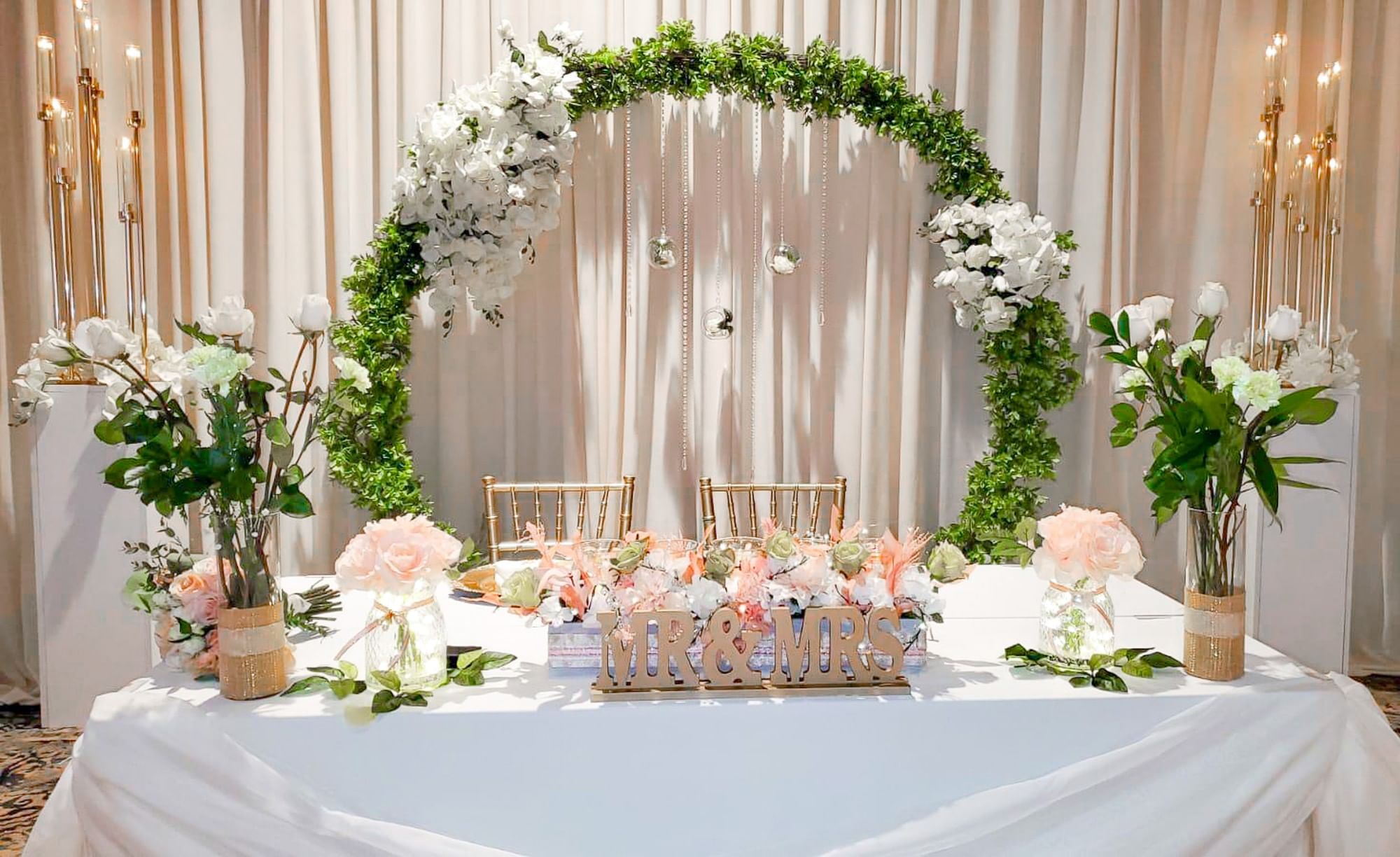 A decorated table with a white tablecloth, flowers, and a decorative arch in the background.