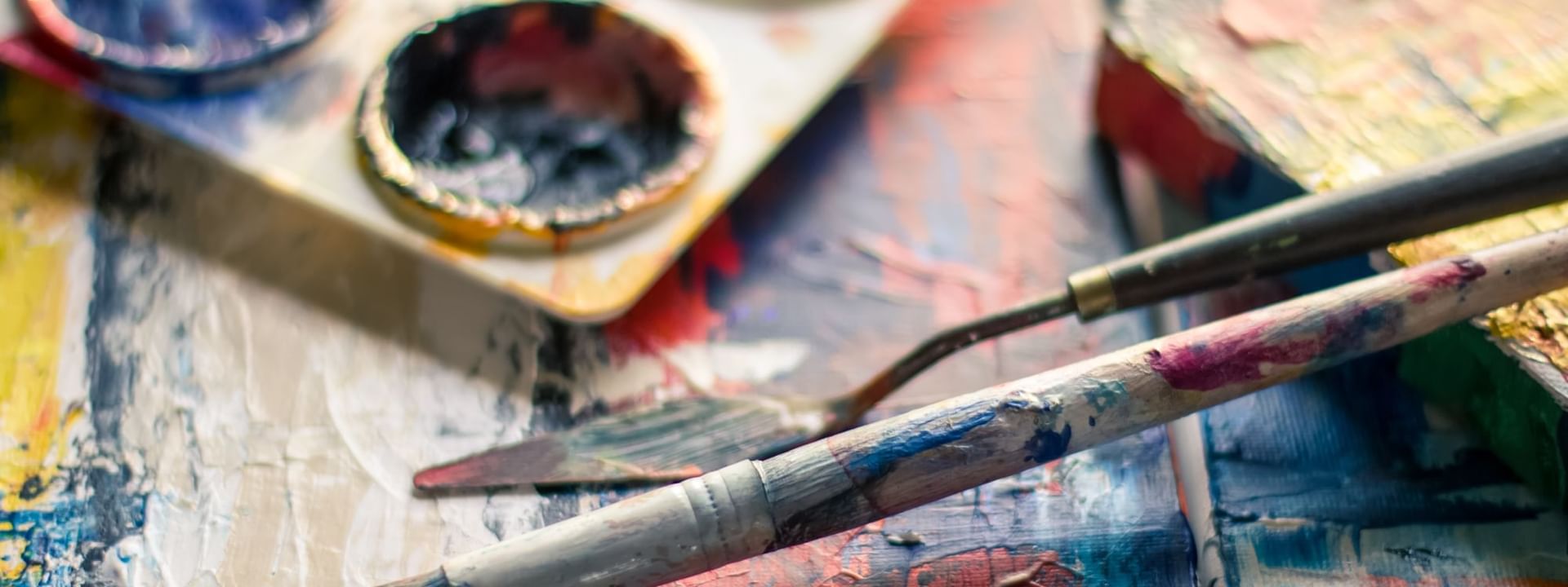 Paint brushes and paint on a wooden table at Kinship Landing