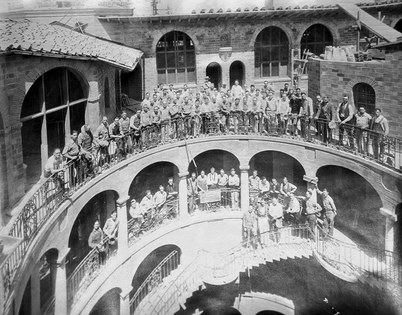 large group of men standing on exterior balcony and stairs of Mi