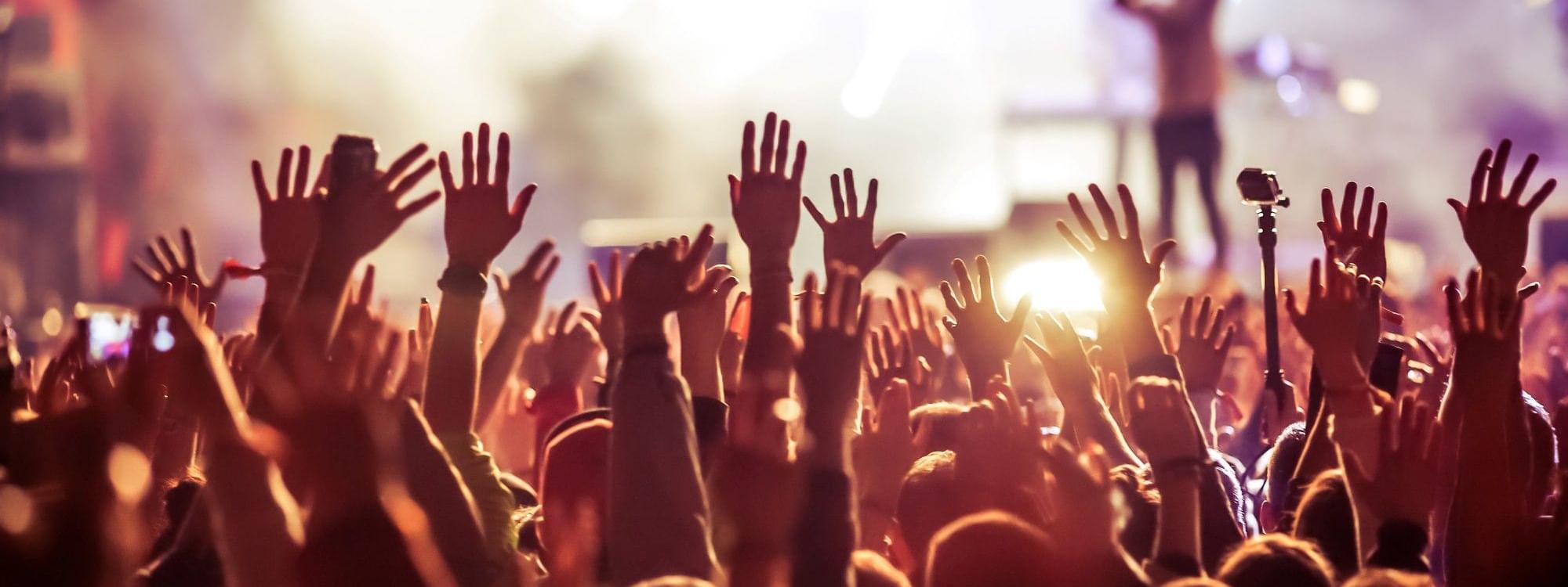 Crowd of people with their hands raised at a concert near Warwick Hotels and Resorts