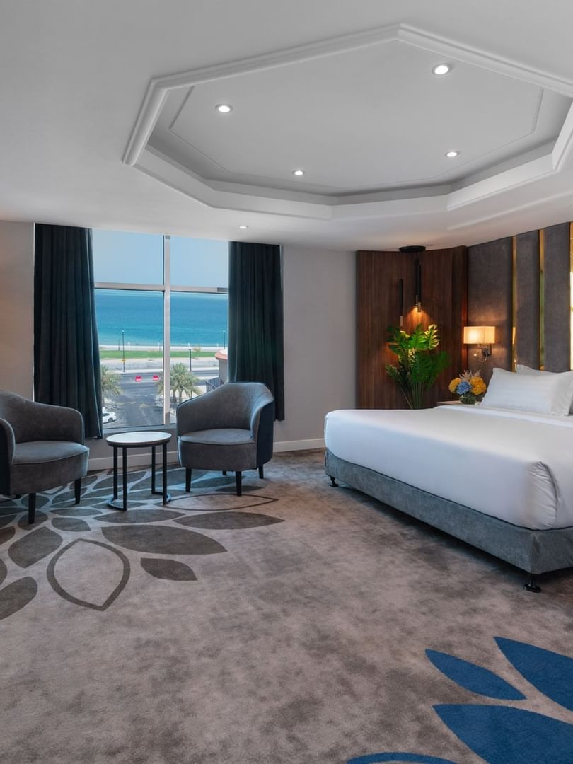 Royal Suite Sea View features King Bed & two grey armchairs by a window at Warwick Al Jubail
