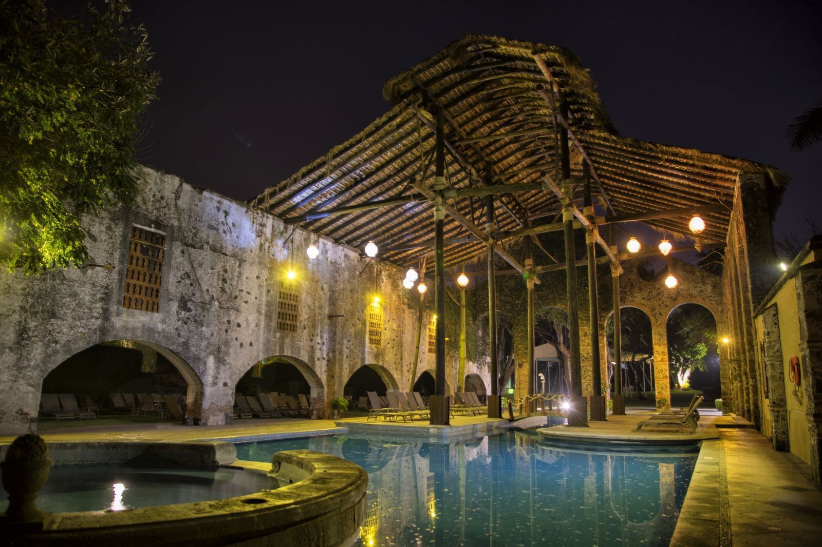 Tumbonas junto a la piscina al aire libre en Fiesta Americana por la noche