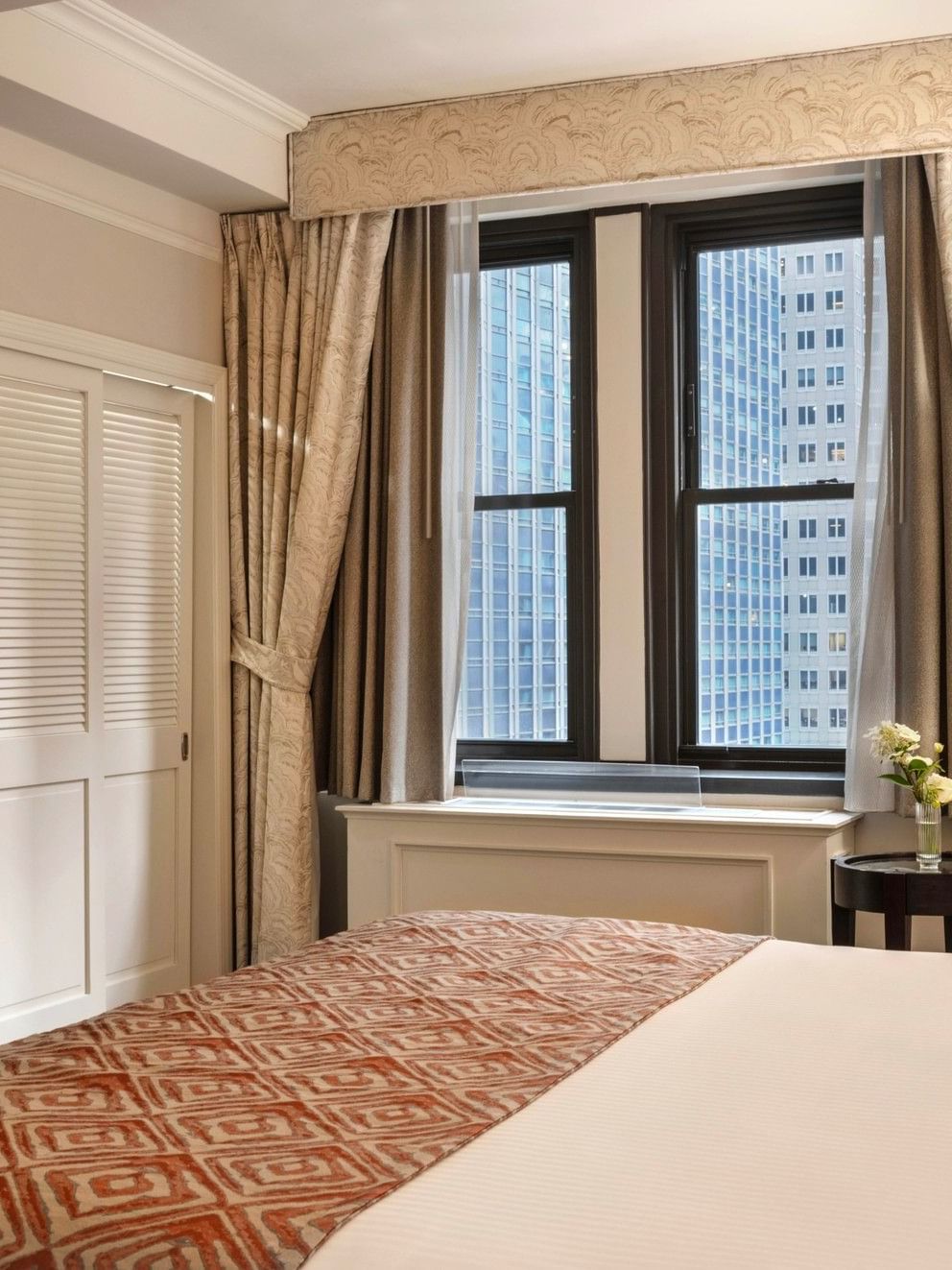 Premier City view room corner view of king bed & louvered closet doors, and city view windows at Warwick New York