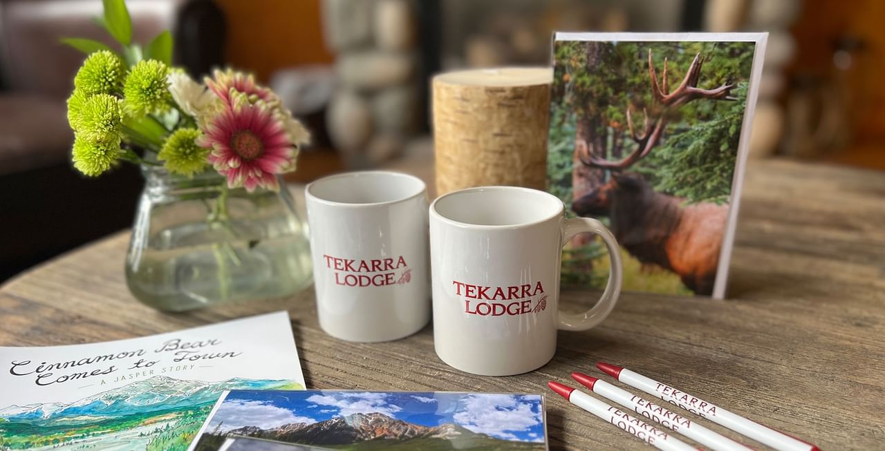 Mugs, pamphlets, pens, and flowers on a desk