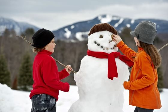 Two young friends building a snowman.