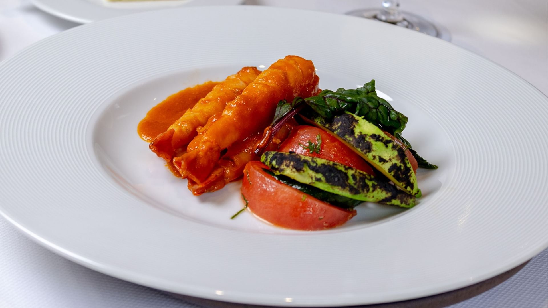 Gourmet plate with orange sauce, grilled avocado, and fresh tomato slices at Quinta Real Oaxaca