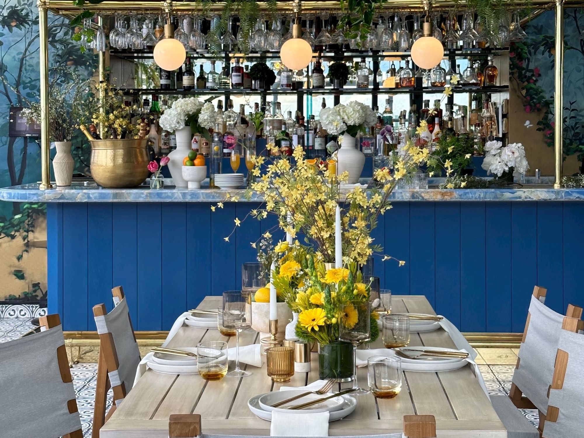 Rooftop Setting with chairs, tables, and bartop with food and floral arrangements