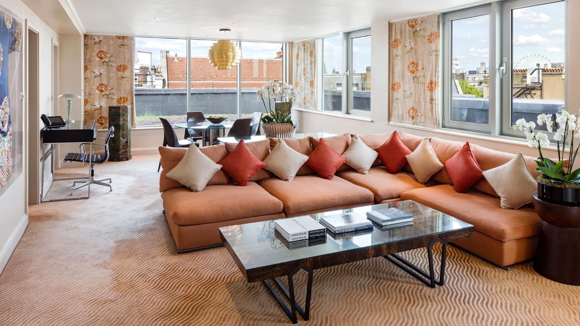 Spacious living room in Saffron Suite at The May Fair Hotel London with a large sofa, glass coffee table, and dining table