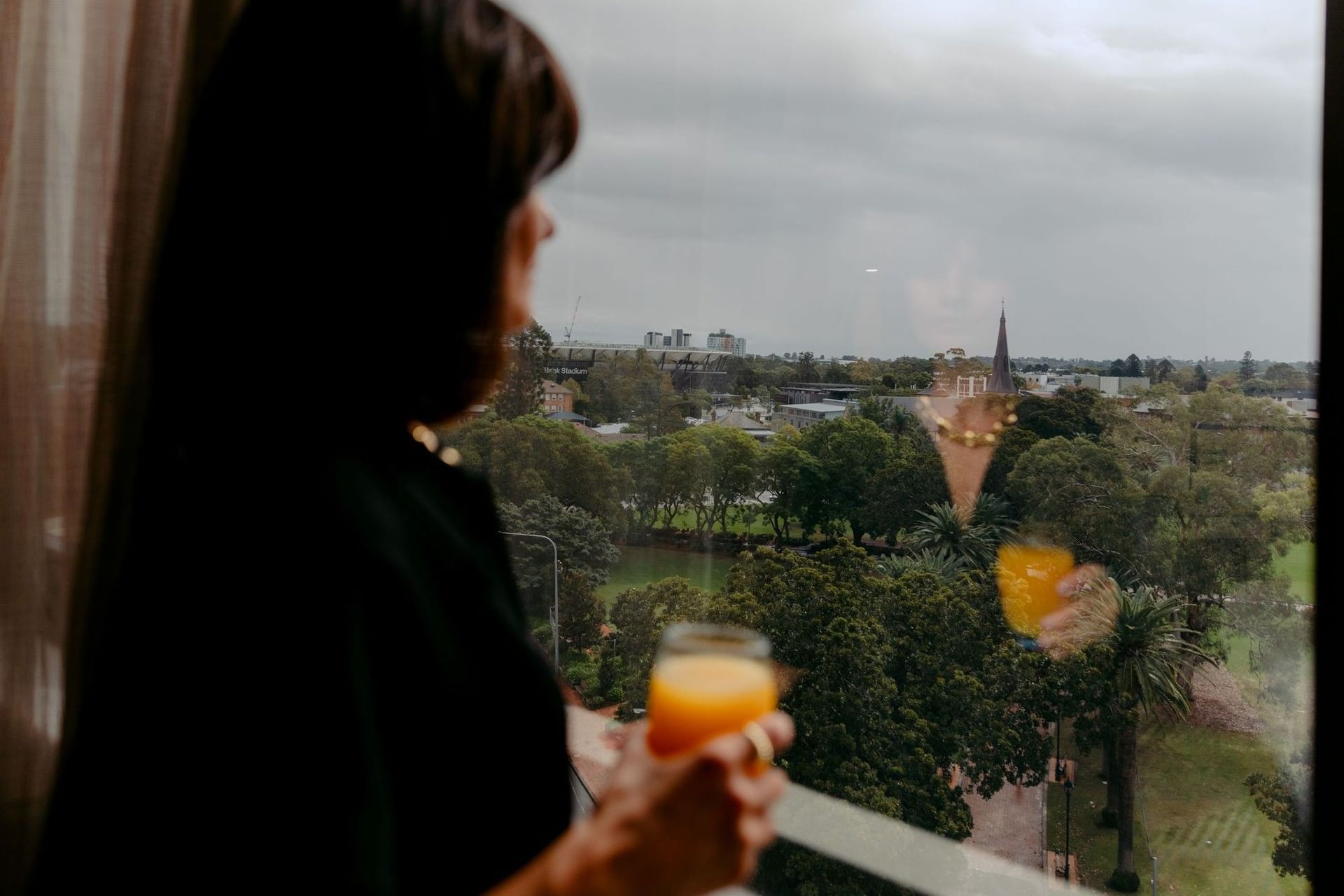 Woman enjoying a drink while looking out the window at Novotel Sydney Parramatta