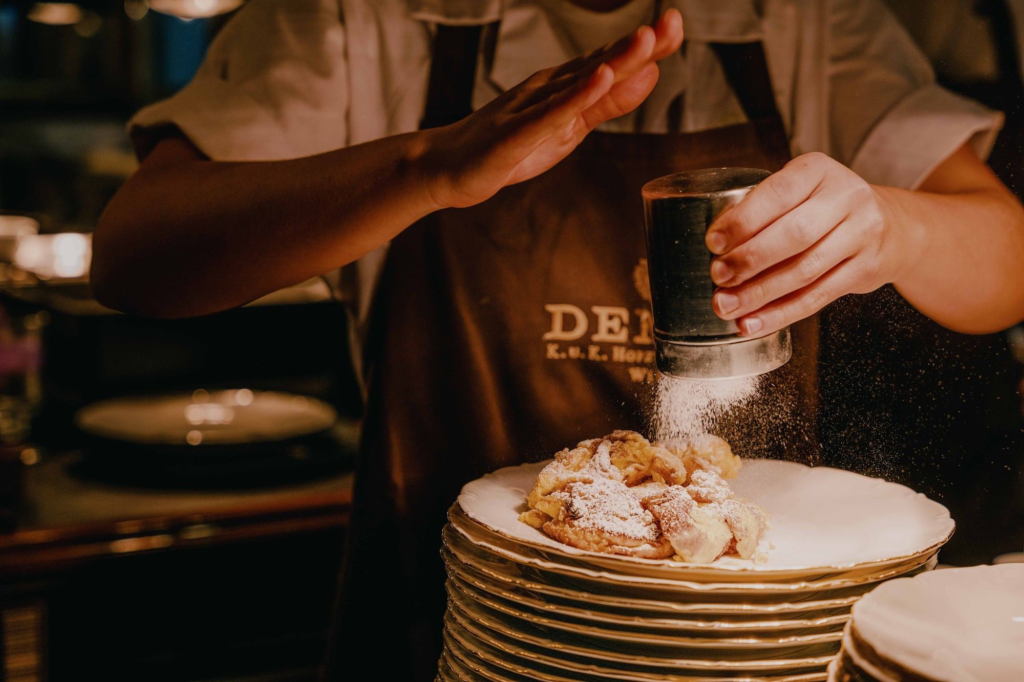 Preparation of a sweet dessert at Café Demel in Vienna with powdered sugar and a warm patisserie atmosphere