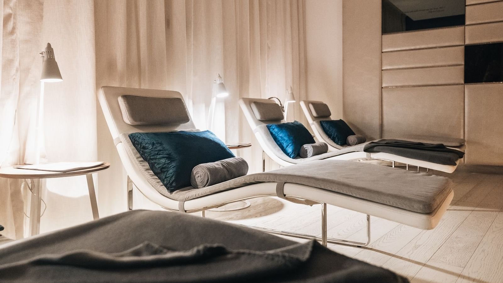 Minimalist relaxation room of Pause Spa with chaise lounges, soft lighting, and plush blue pillows at Paramount Hotel Dubai