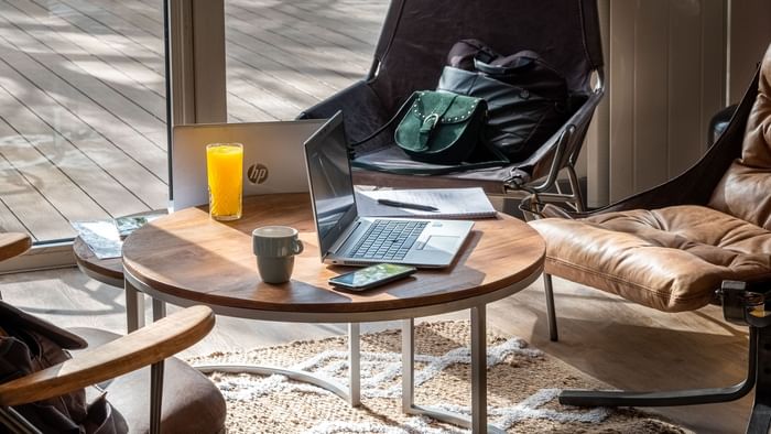 A laptop on a table with notepad & a juice at Originals Hotels