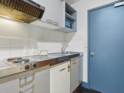 Compact kitchen with stove, sink, and refrigerator at Student Living Auckland - Beach.