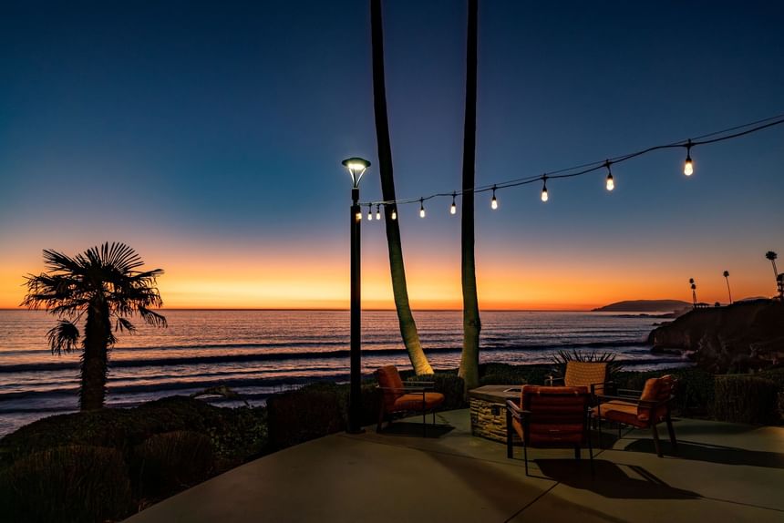 Hotel terrace fire pit with seating at sunset on the ocean 