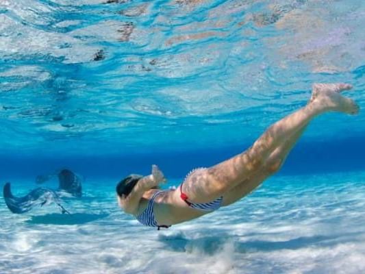 Woman snorkeling in crystal-clear water at Stingray City near The Residences at Seafire in Cayman Island.
