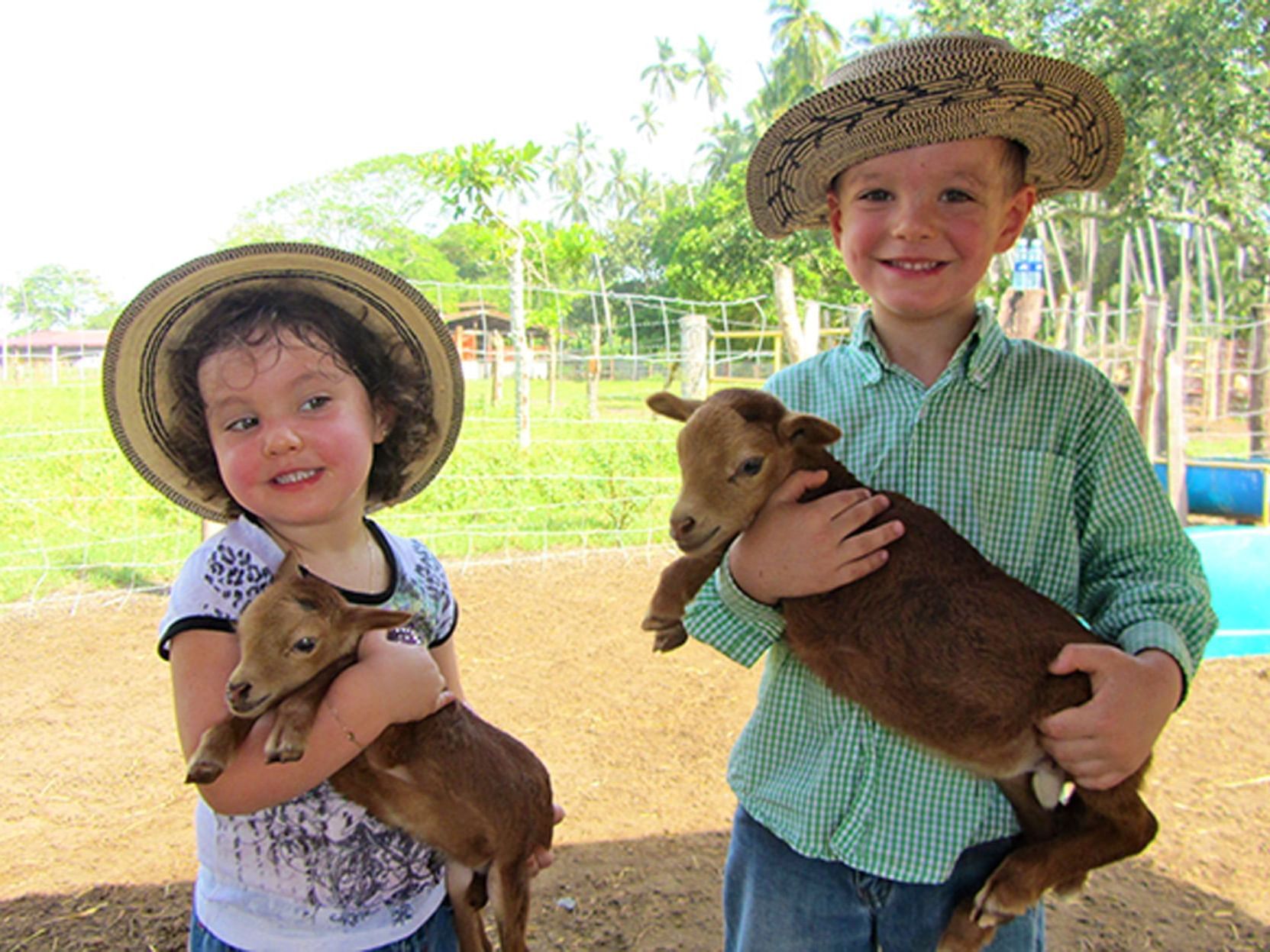 Two children holding baby goats on a Farm Tour near Las Olas Beach Resort in Panama day tours