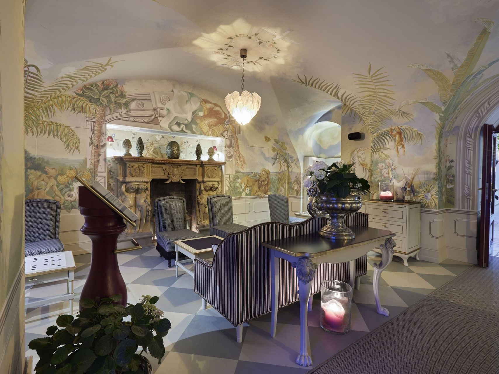 Lobby with mural walls, striped floor, fireplace, furniture, and a hanging chandelier casting a circular light.