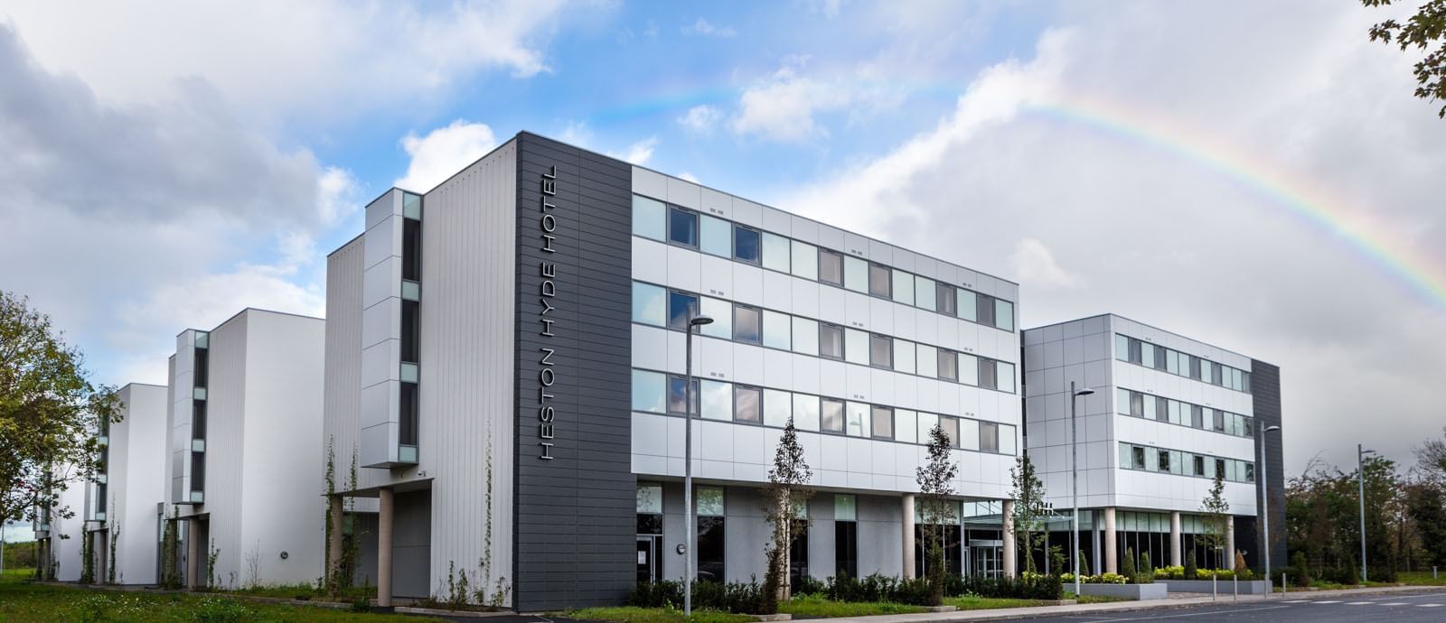 Exterior of Heston Hyde Hotel featuring modern architecture with large windows and a parking area