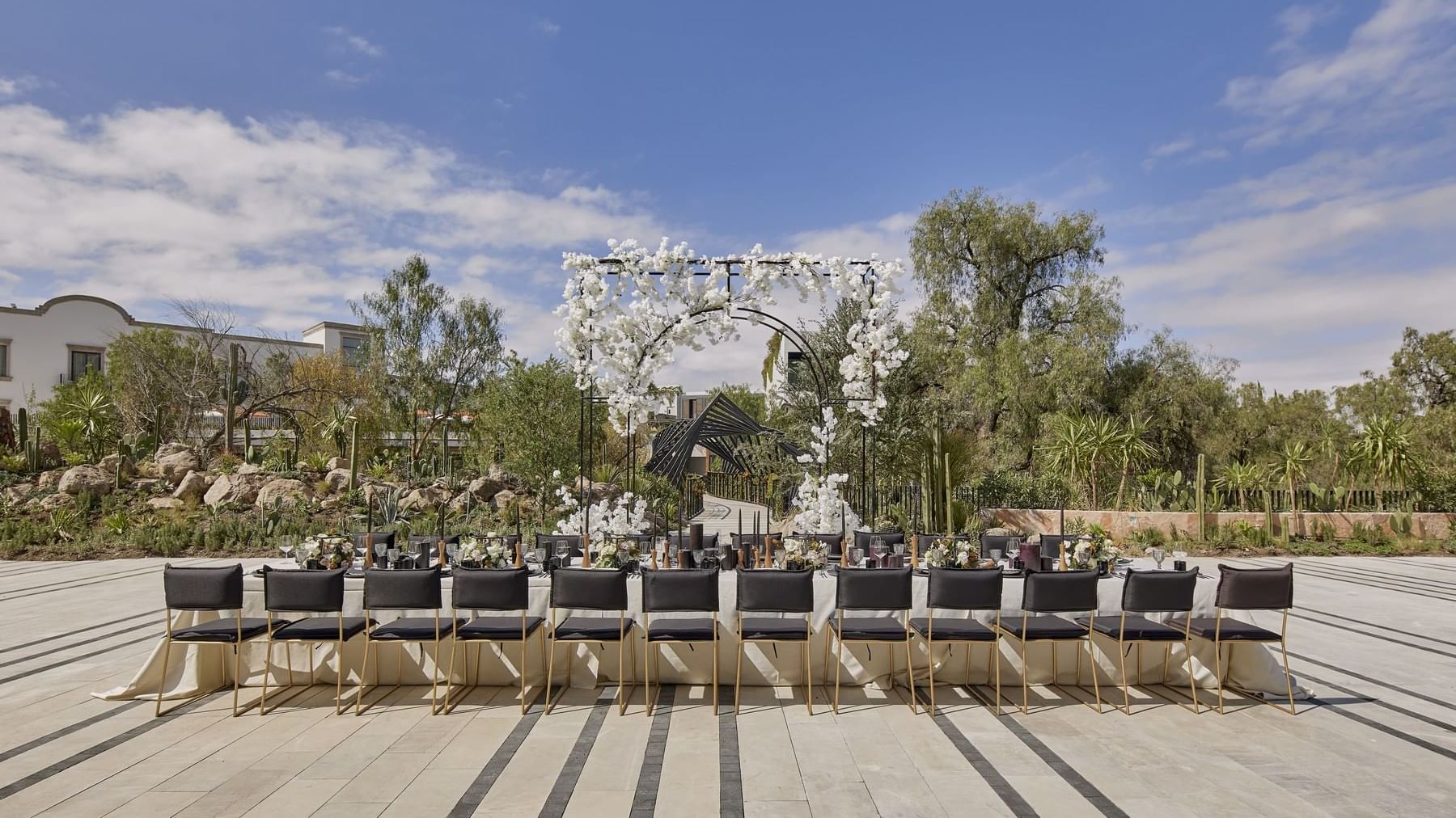 Outdoor event set up with a long dining table, chairs, and a floral arch at Live Aqua San Miguel de Allende