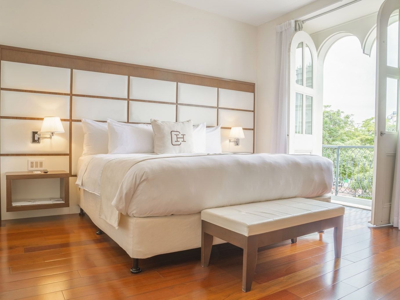 Suite elegante con cama grande, cabecera decorativa y ventanas arqueadas en Central Hotel Panama Casco Viejo.