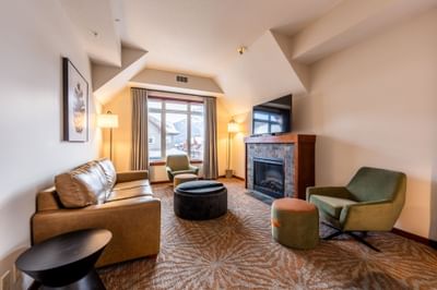 Living room with cozy loungers, TV, and a fireplace in Two Bedroom Mountain View Suite at Blackstone Mountain Lodge