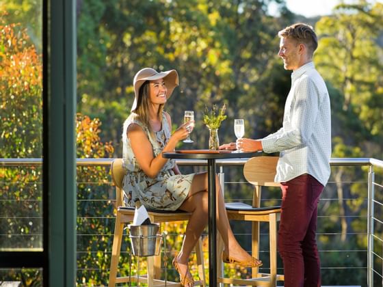 Couple having champagne on the balcony at Cradle Mountain Hotel