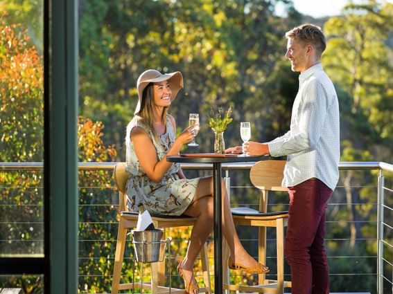 Couple having champagne on the balcony at Cradle Mountain Hotel