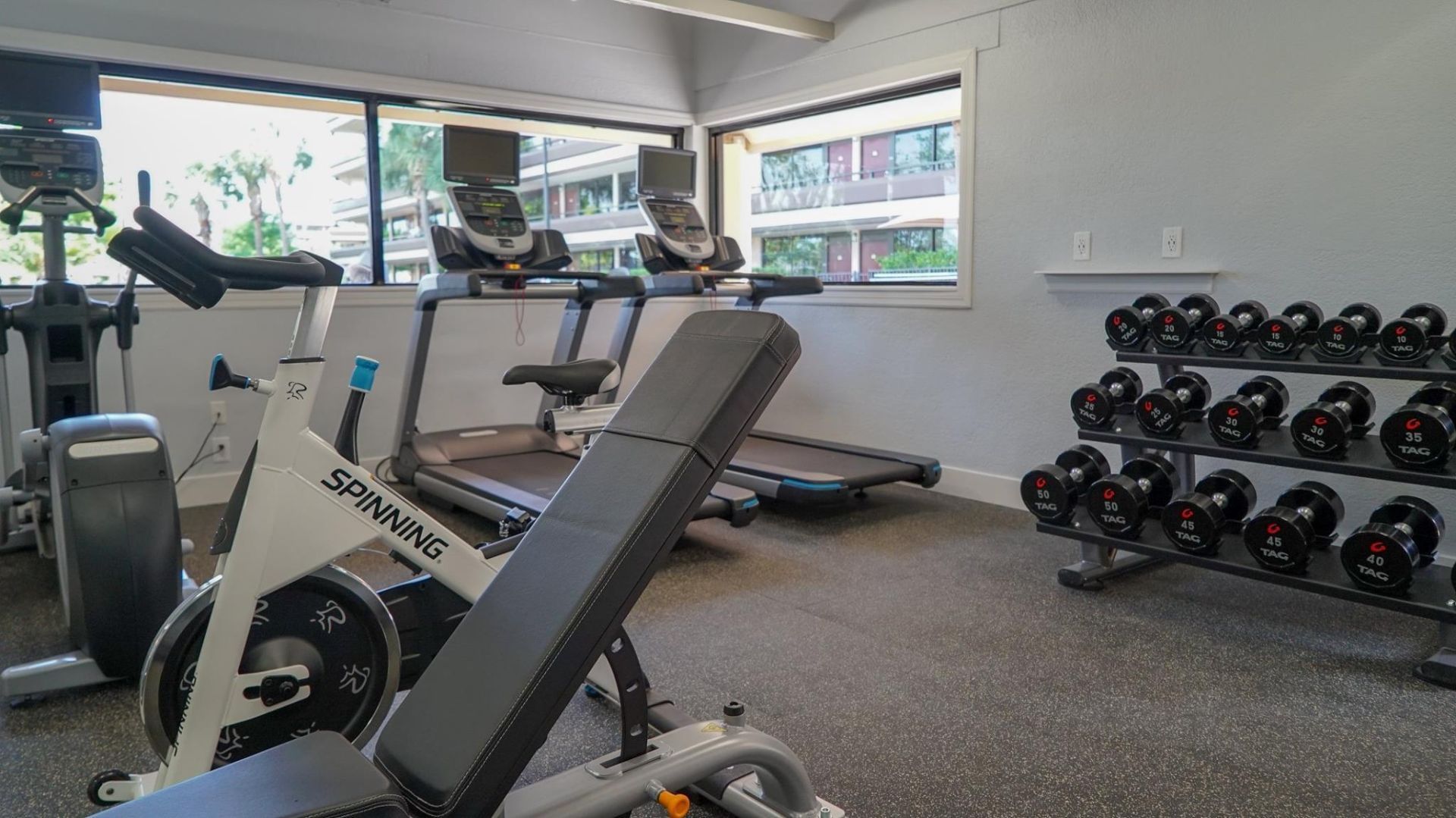 A gym with exercise equipment including treadmills and dumbbells.