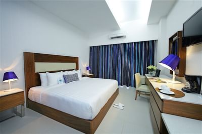 A clean and comfortable hotel room at Hotel Mykonos with a king-sized bed and a modern desk