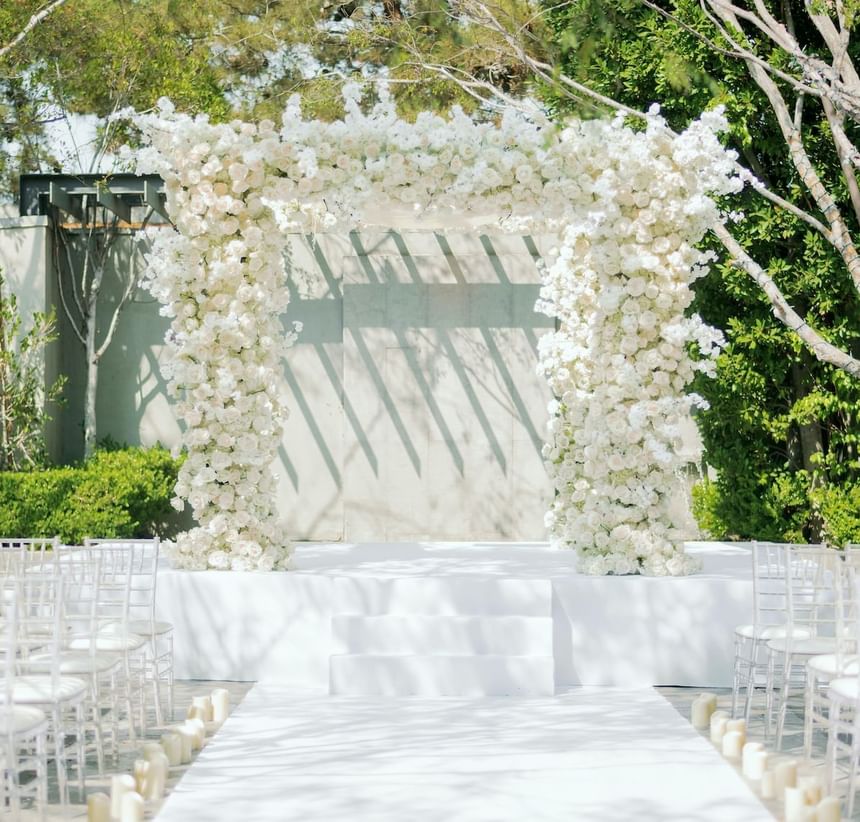 A wedding ceremony set-up with a floral arch at Luxe Sunset Boulevard Hotel