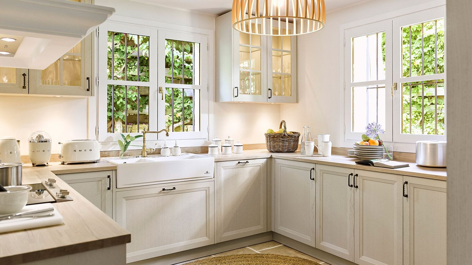 Bright kitchen with light grey cabinets and a white sink placed under two large windows at the Marbella Club